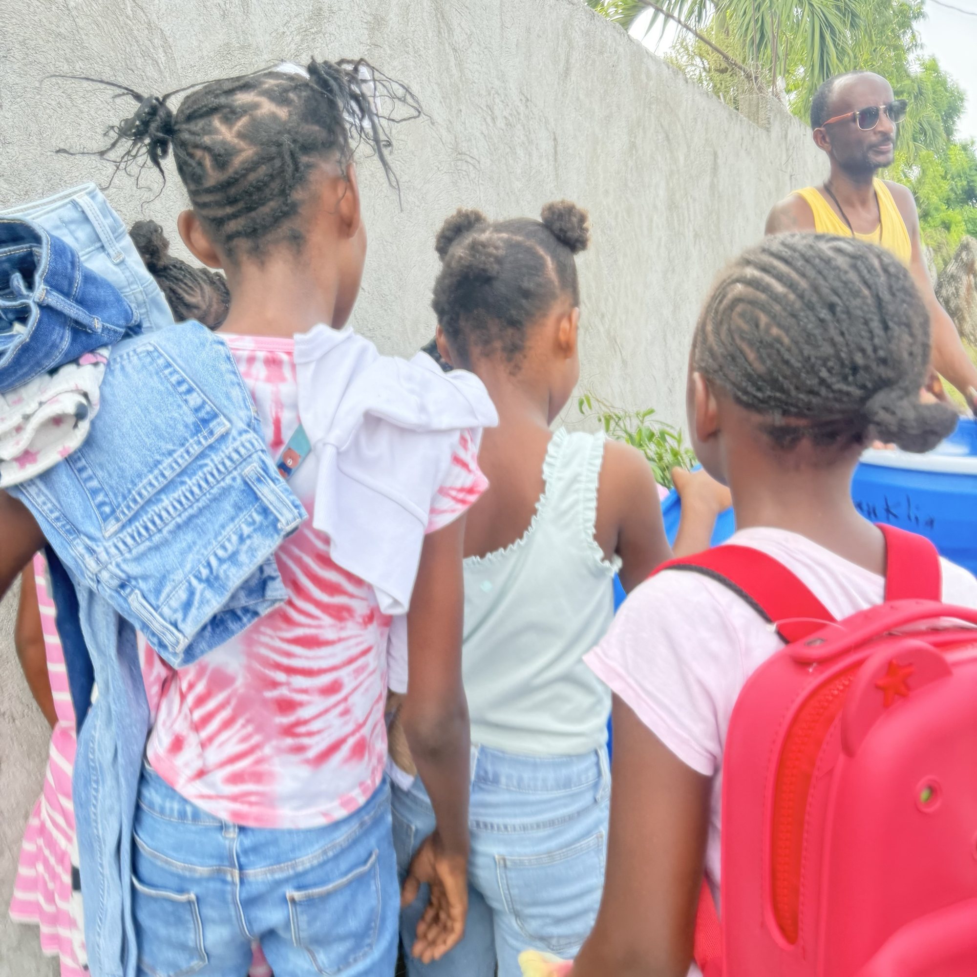 Children carrying clothing and school bags away from the distribution table.