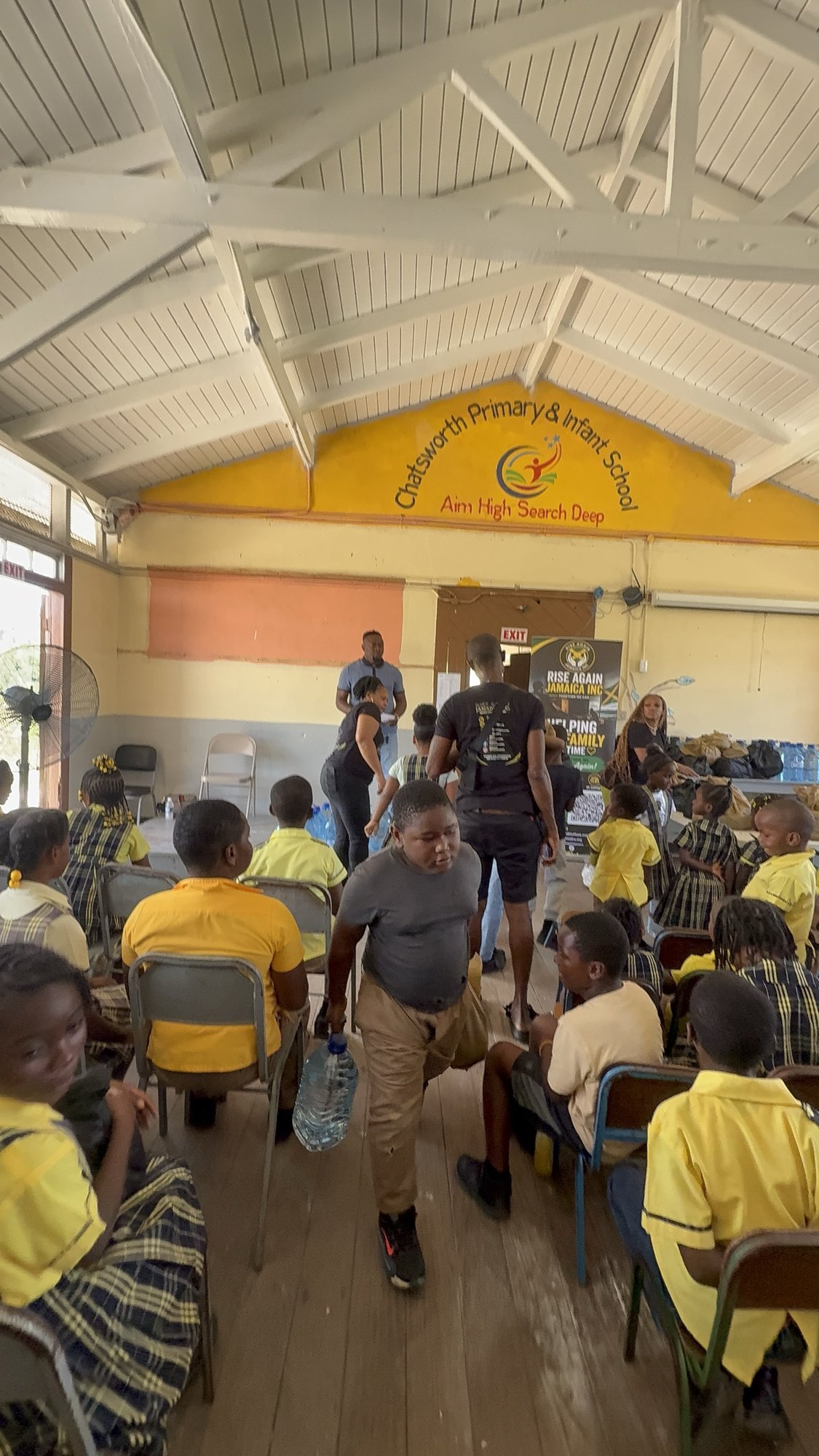 Volunteers distributing food packages to students in the school hall.