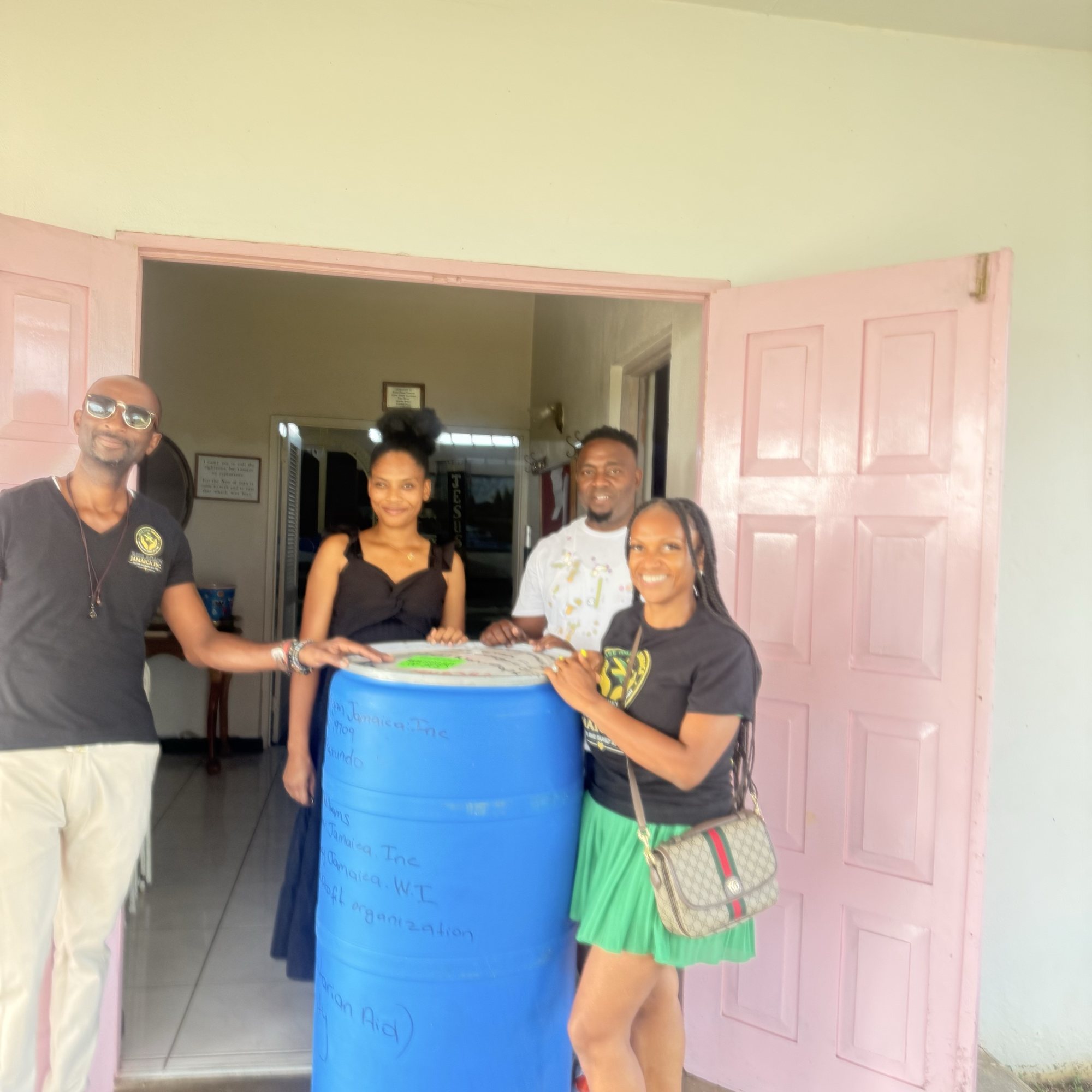 Rise Again Jamaica Incorporated team members handing over a barrel of clothing at Prospect Community Church in Trelawny.