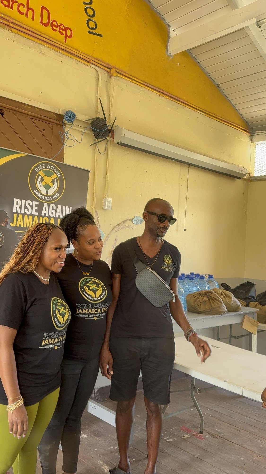 Rise Again Jamaica Incorporated team members in branded shirts at a school outreach.