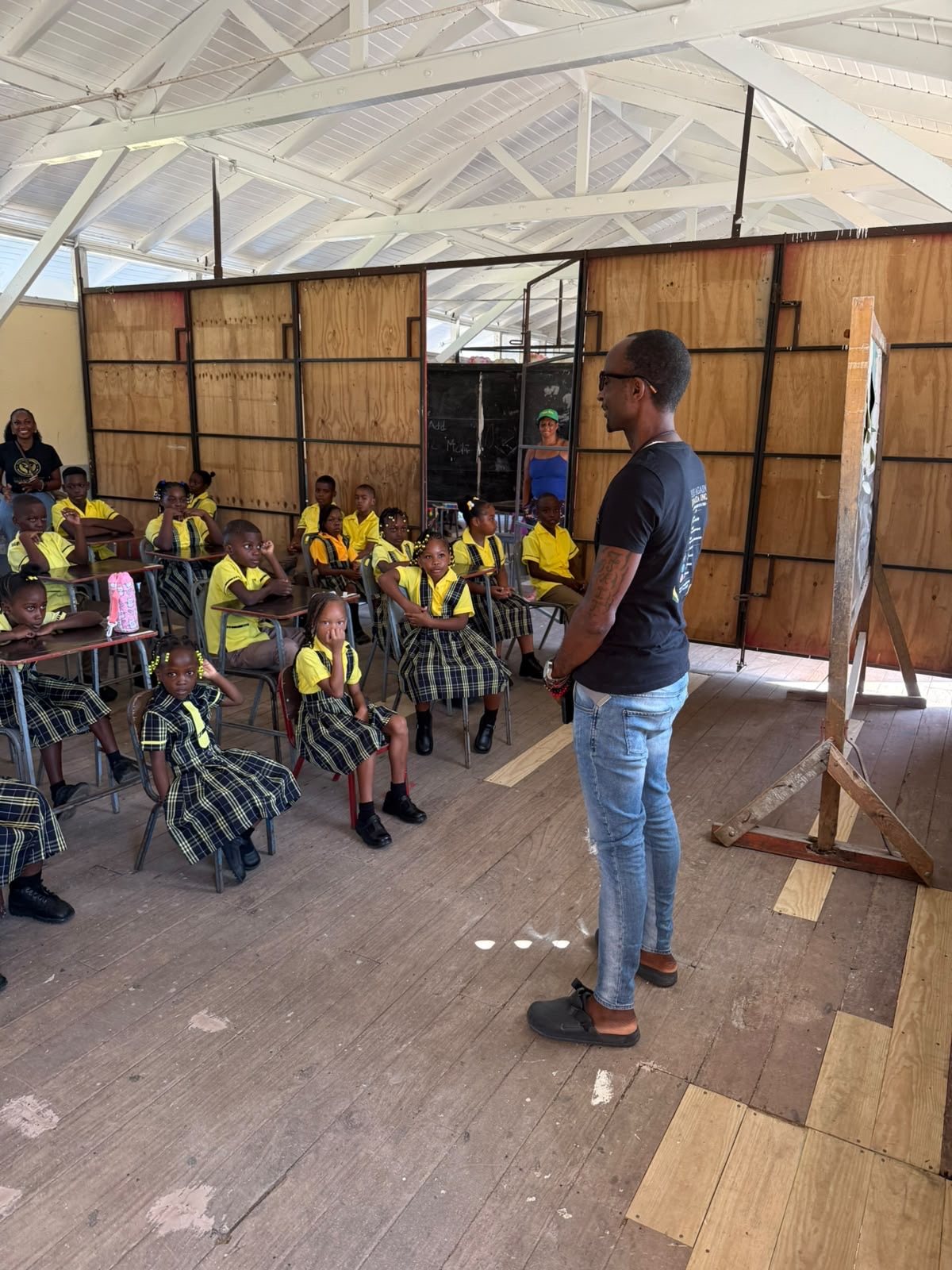 A Rise Again Jamaica Incorporated team member speaking with students in a classroom during the back to school visit.