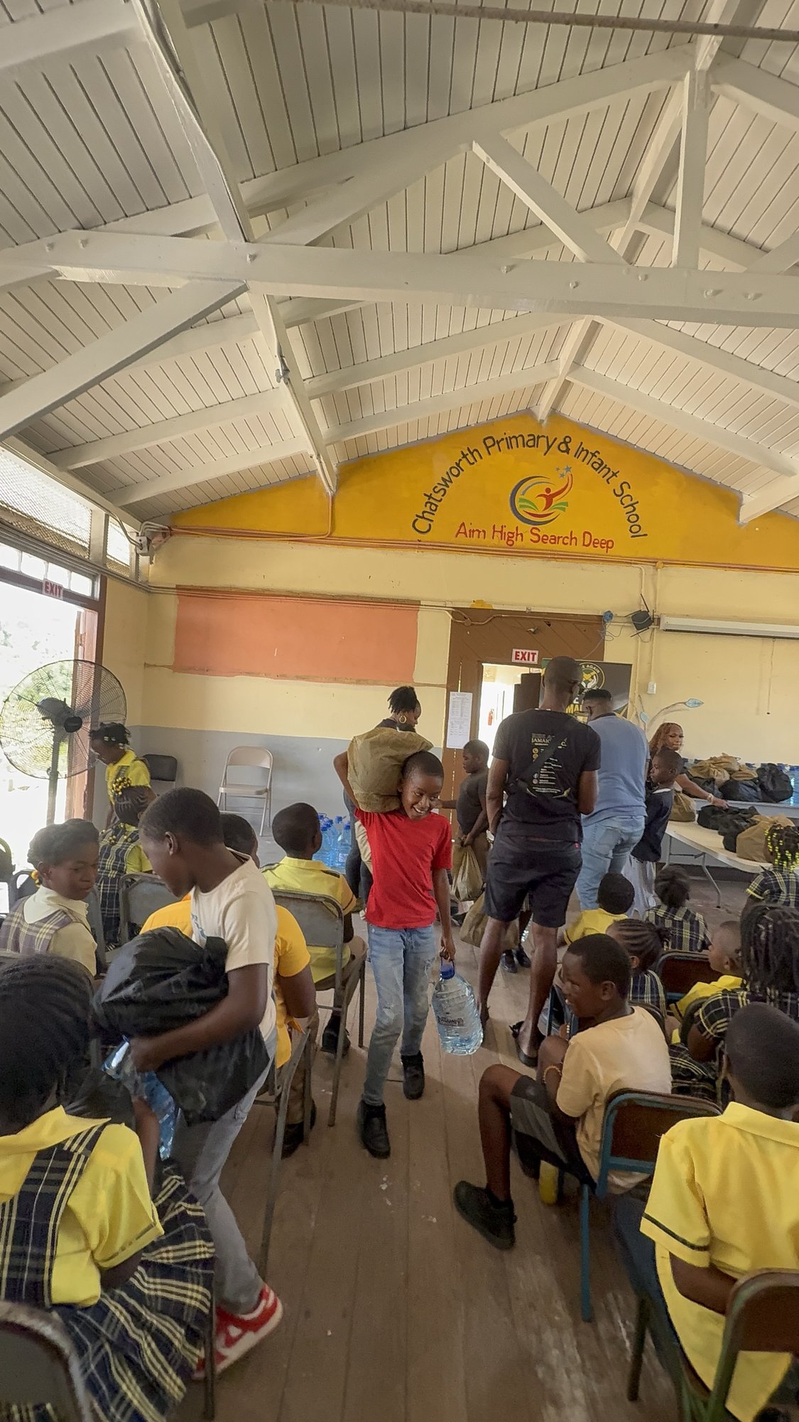 A student carrying home a food package and drinking water during a Rise Again Jamaica Incorporated distribution.