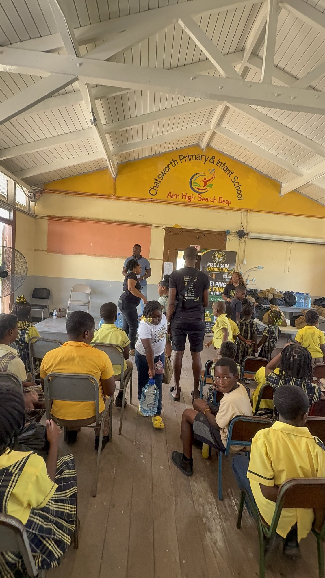Students collecting food packages and bottled water inside the school hall at Chatsworth Primary and Infant School.